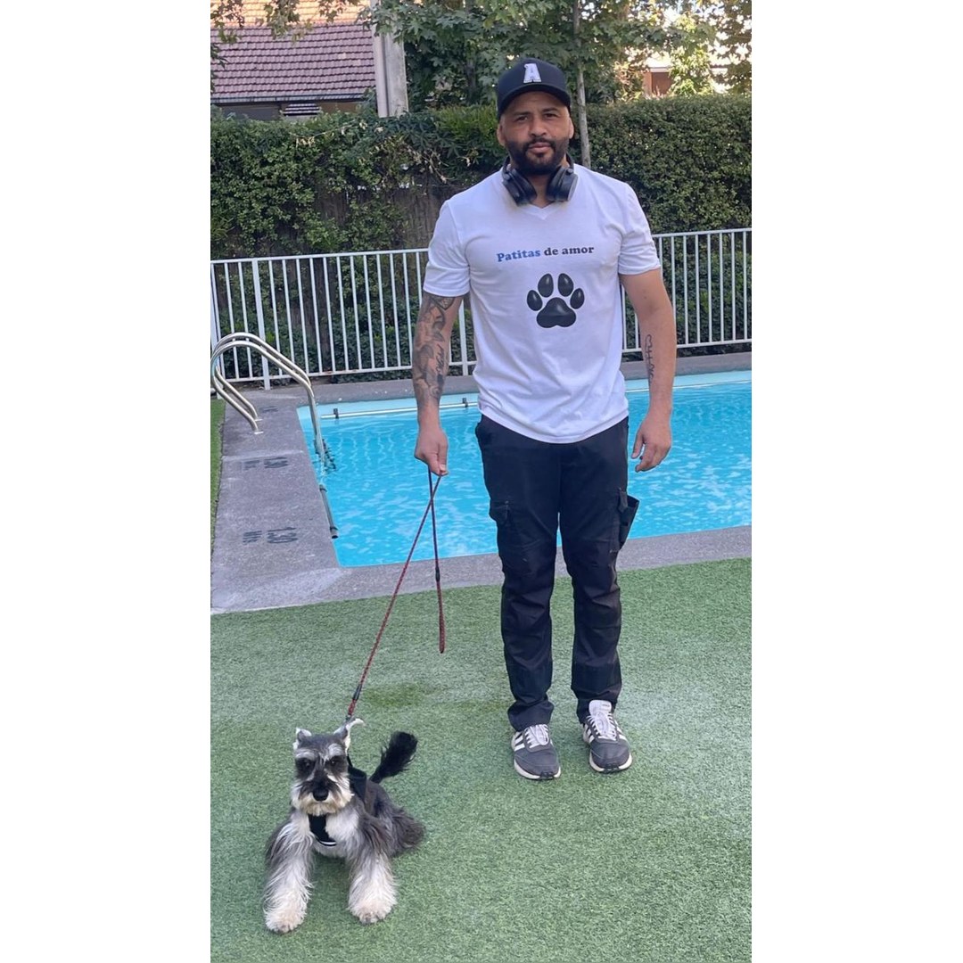 Perro criollo negro paseando con arnés por parque de San Miguel